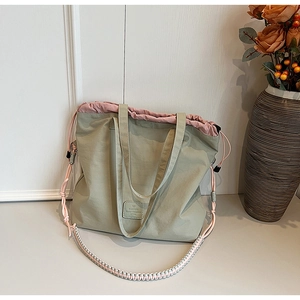 Detail of light green tote bag featuring drawstring closure and woven lanyard strap