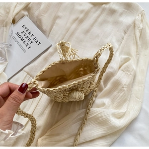 Detail showing the natural straw texture, woven strap and soft fabric lining of the beige bag
