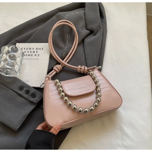 Detail of light pink shoulder bag with silver bead chain handle and textured finish