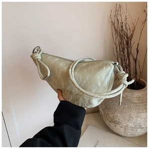 Detail of light green pleated handbag featuring knotted rope handles and silver rings