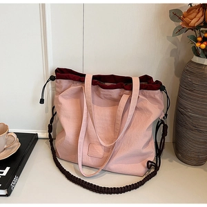 Detail of light pink canvas tote with burgundy drawstring closure and woven strap