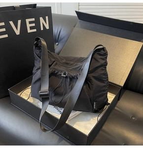 Detail of adjustable nylon strap and drawstring on large black tote bag in gift box