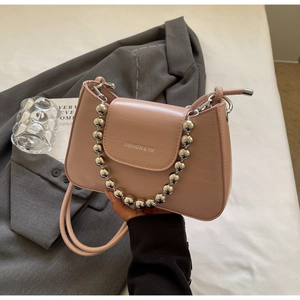 Detail of pink croc-embossed underarm bag with silver ball chain and logo on grey blazer