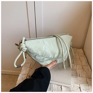 Detail of pistachio green dumpling bag featuring pleated texture and knotted shoulder strap