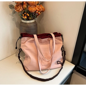 Detail of pink canvas tote showing drawstring closure and brown braided shoulder strap