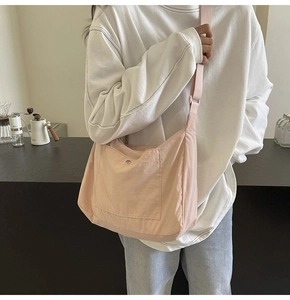 Close-up of lightweight light pink fabric crossbody bag with wide strap and front snap pocket