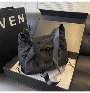 Detail view of the black nylon drawstring tote bag with an adjustable wide shoulder strap