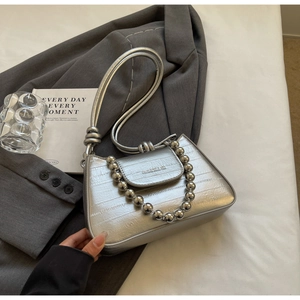 Macro detail of silver crossbody bag featuring metallic bead chain and textured finish