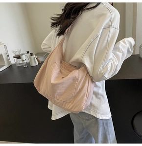 Detail of light pink canvas tote bag featuring an outer pocket and silver snap button