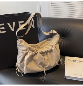Detail of light gray nylon tote bag with drawstring folds and adjustable shoulder strap