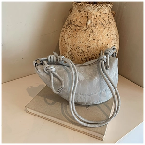 Close-up of light grey dumpling bag with pleated leather texture and knotted strap