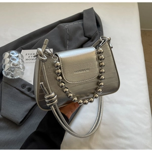 Close-up of silver crossbody bag with metal bead chain and textured leather finish