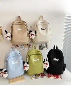 Detail of five multi-colored school backpacks with cute plush puppy keychains