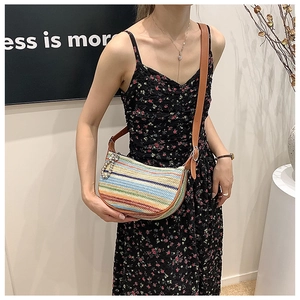 Detailed view of colorful striped straw shoulder bag with adjustable brown leather strap