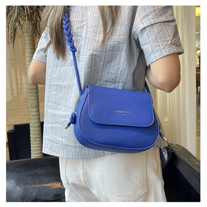 Detail of royal blue leather crossbody bag with woven shoulder strap and gold logo