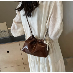 Détail du sac seau en similicuir marron avec bandoulière chaîne et breloque en perles