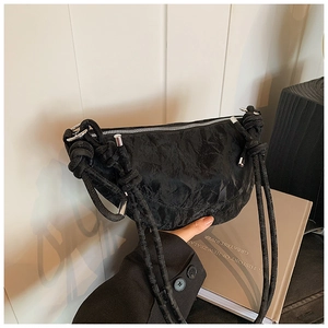 Detail of black crescent shoulder bag featuring premium wrinkled texture and knot strap design