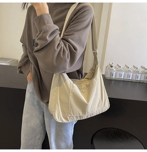 Detail of beige crescent nylon bag with front snap pocket on model for daily use