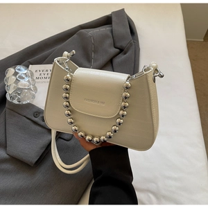Detail of cream crocodile embossed handbag with oversized silver bead metal handle