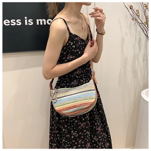 Rainbow striped woven half-moon bag featuring a brown leather strap shown on a model