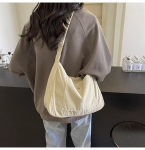 Detailed close-up of a cream canvas crescent crossbody bag showing fabric texture and snap pocket