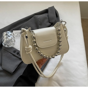Detail of cream white PU leather bag with silver bead chain on dark grey suit