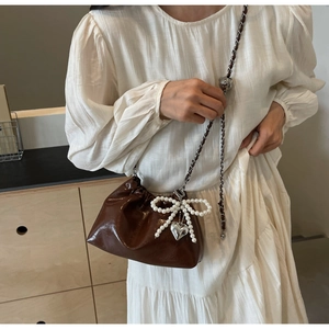 Détail du sac seau plissé marron foncé avec nœud en perles et pendentif cœur argenté