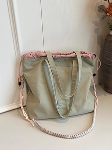 Green canvas tote bag with pink drawstring closure and decorative braided shoulder strap