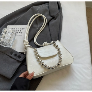 Detail of white crocodile texture bag with silver bead chain and fashion logo