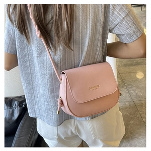 Detail view of a pink saddle bag with golden lettering and stylish knotted shoulder strap