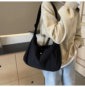 Detail of black nylon hobo bag with adjustable strap and silver snap button on front pocket