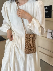 Handwoven straw cell phone bag with tassel detail and openwork mesh for beach vacation