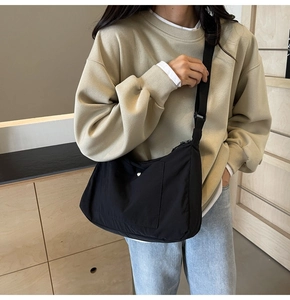 Lifestyle shot of lightweight black nylon crossbody bag with adjustable strap and front pocket