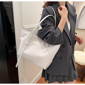 Detail showing the white woven texture and flat shoulder strap of the tote bag