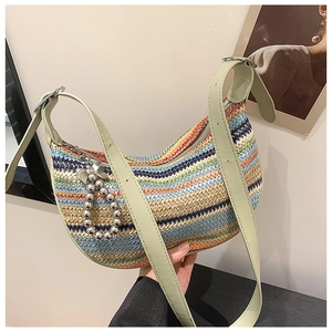 Macro detail of multi-color woven straw bag with green leather strap and bow charm