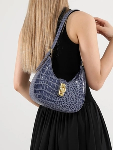 Sac hobo bleu à motif crocodile porté par un mannequin pour un look d'été élégant