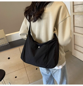 Rear view of a minimalist black nylon crossbody bag with wide strap for daily commute