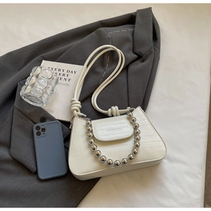Detailed view of white crocodile-textured underarm bag with silver bead chain accessory