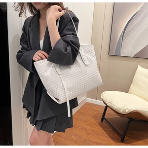 Detail of white woven leather tote bag carried by a model in casual office attire