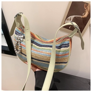 Close-up of colorful wavy woven straw bag with green strap and bow charm detail