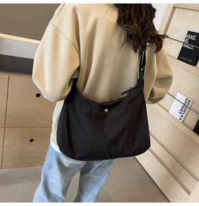 Detail of black nylon crossbody bag with snap button pocket and adjustable shoulder strap