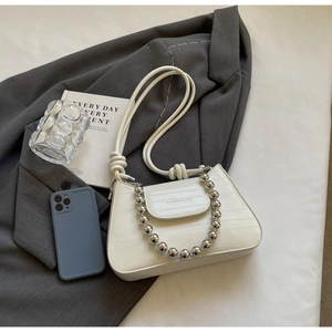 Detail of white crocodile texture baguette bag with silver bead chain on grey blazer
