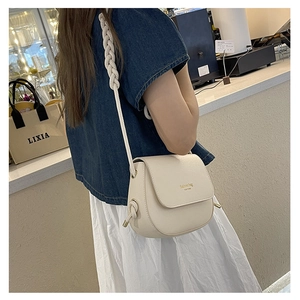 Detail of cream saddle crossbody bag with thick woven rope strap and gold fashion logo