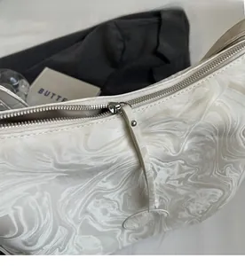 Détail de la fermeture éclair argentée et texture marbre du sac cabas