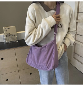 Close-up of a purple crossbody bag with metal snap pocket and adjustable shoulder strap