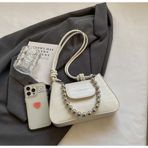 White faux-crocodile leather shoulder bag featuring silver bead chain on a grey blazer