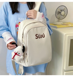 Detail of off-white backpack with cartoon dog charm and Sj logo in indoor setting