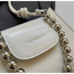 Close-up of the silver bead chain and the brand logo on this cream crossbody bag