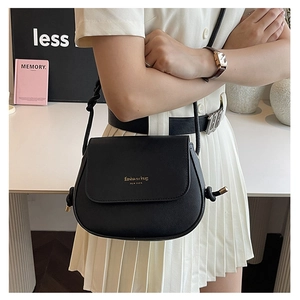 Detail of black faux leather crossbody saddle bag featuring gold fashion typography