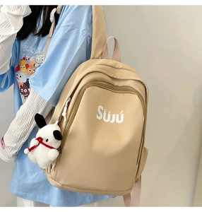 Close-up of beige nylon backpack with Suju logo and a cute white plush puppy pendant